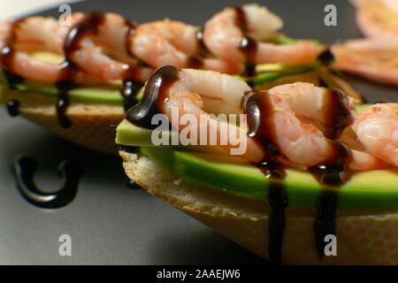 Bruschetta mit Garnelen, Avocado und Kalk auf einen dunklen Platte Stockfoto