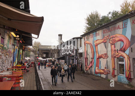 Menschen besuchen die RAW-Gelände Bereich Berlin im Volkspark Friedrichshain Nachbarschaft. Alte Lagerhäuser enthalten jetzt Cafés, Nachtclubs, Kletterwände und vieles mehr. Stockfoto