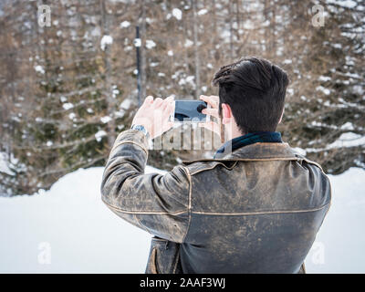 Junger Mann mit Smartphone im Schnee Stockfoto