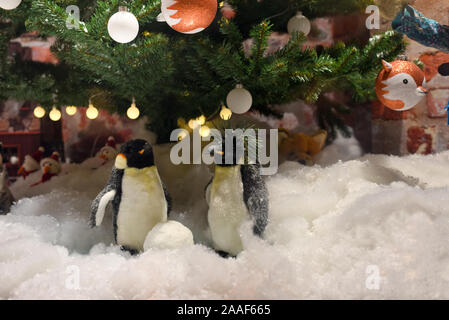 Festliche neues Jahr feier Zusammensetzung, Pinguine im Schnee und einen Weihnachtsbaum mit einem Kranz und Dekorationen im Hintergrund Stockfoto