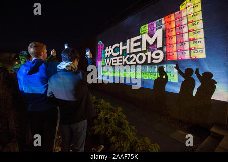 Studenten halten Handys gegen einen hellen Display an der Universität St Andrews, die die periodische Tabelle der lebt in Unterstützung der Chemie Woche kommen. Stockfoto