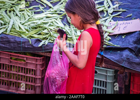Nahaufnahme eines Mädchens herauf Auberginen in Farmers Market in Katerini. Malerischer Blick auf einen typischen Tag in Farmers Market in Katerini Stadt. Stockfoto
