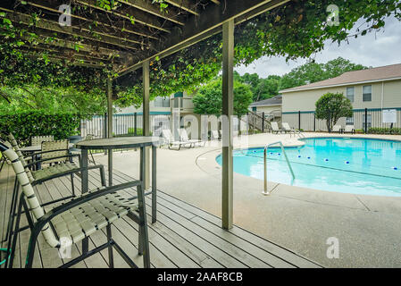 Der Pool verfügt über einen Sitzbereich im Freien mit einer Pergola auf Robinwood Apartments in Mobile, Alabama. Stockfoto