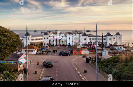 Die Fassade der Clacton Pier mit den Besuchern im Vordergrund und die Windenergieanlagen von Gunfleet Sands Offshore Windpark in der Nordsee hinter sich. Stockfoto