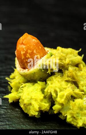 Wasabi Coated Peanuts auf Schiefer. Japanische Wasabi Gewürz. Grüne Wasabi Erdnüsse auf einer schwarzen Platte auf einem dunklen Hintergrund. Stockfoto