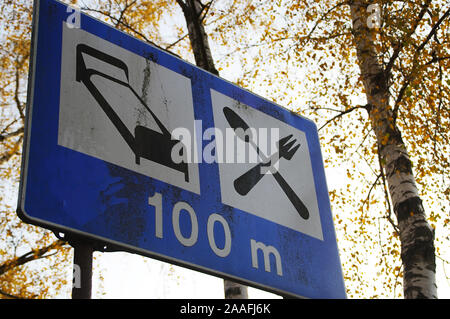 Schild am Straßenrand Hotel und Restaurant auf dem Hintergrund der Bäume. Alte, beschädigte Wegweiser durch die Straße. Stockfoto