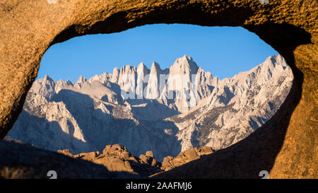 Blick auf den Mount Whitney und die Bergsteiger durch einen Torbogen aus Sandstein in der Wüste in der Nähe von Bishop, Kalifornien suchen Route. Stockfoto