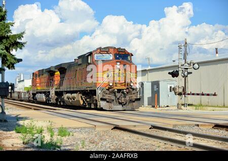 Plano, Illinois, USA. Ein Burlington Northern Santa Fe Güterzug, geführt von zwei Lokomotiven kreuzt ein Bahnübergang in Plano, Illinois. Stockfoto