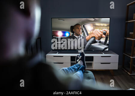 Afrikanischer Mann auf Sofa mit Fernbedienung In der Hand Stockfoto