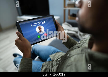 Close-up In eines Mannes Hand Digital Tablet mit Arzt, der eingehende Anruf auf der Anzeige Stockfoto