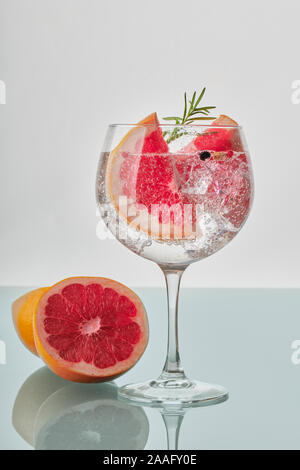 Ein Glas Gin und Tonic mit Scheiben von Grapefruit, grünen Rosmarin, Eiswürfel und Fizz Stockfoto