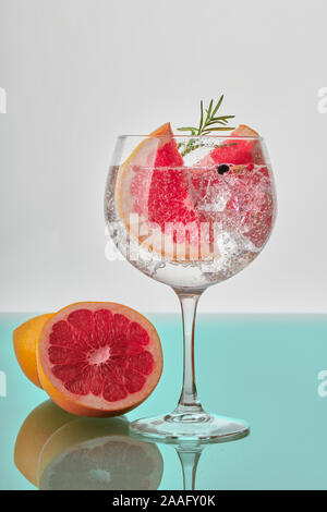 Ein Glas Gin und Tonic mit Scheiben von Grapefruit, grünen Rosmarin, Eiswürfel und Fizz Stockfoto