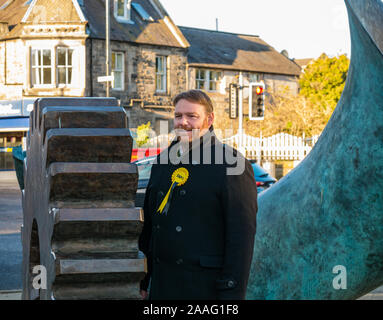 Loanhead, Midlothian, Schottland, Vereinigtes Königreich: 2019 Bundestagswahlkampf SNP Kandidat Owen Thomson Kundenwerbung neben Bronze cog Artwork Stockfoto