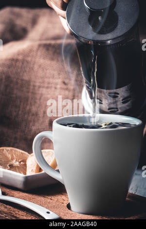 Strömenden heißen Kräutertee in weiße Krug Stockfoto