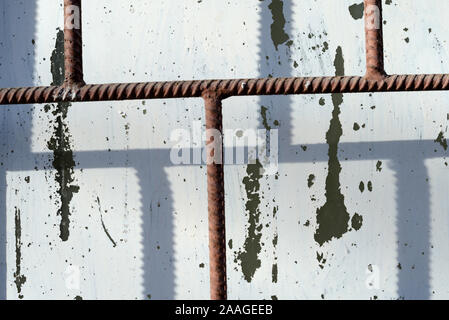 Fragment eines alten Fenster durch weiße Farbe hinter einem rostigen Braun bars an einem sonnigen Tag gemalt. Zusammenfassung Hintergrund Stockfoto