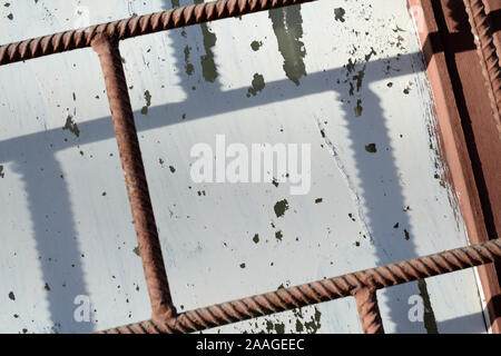 Fragment eines alten Fenster durch weiße Farbe hinter einem rostigen Braun bars an einem sonnigen Tag gemalt. Zusammenfassung Hintergrund Stockfoto