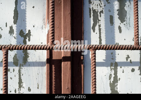 Fragment eines alten Fenster durch weiße Farbe hinter einem rostigen Braun bars an einem sonnigen Tag gemalt. Zusammenfassung Hintergrund Stockfoto