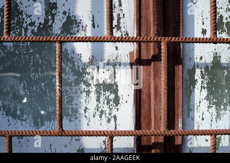 Fragment eines alten Fenster durch weiße Farbe hinter einem rostigen Braun bars an einem sonnigen Tag gemalt. Zusammenfassung Hintergrund Stockfoto