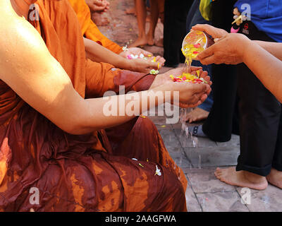 Während der Songkran Festival. Leute richten in der Linie für Baden Mönche. Durch die Verwendung einer kleinen Schüssel Wasser zu schaufeln bestreut mit verschiedenen duftende Blume pe Stockfoto