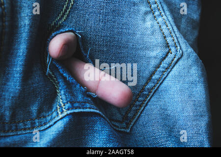 Abgenutzte Gesäßtasche seiner Jeans mit den Fingern. Hippie Style. Alte und moderne Kleidung. Stockfoto