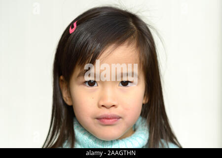 Ernsthafte hübschen kleinen asiatischen Mädchen in Blau rollkragen pullover direkt in die Kamera schaut in eine Nahaufnahme Kopf portrait Stockfoto