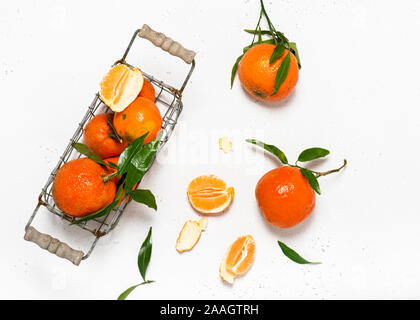 Blick von oben auf die rustikale Metall Korb mit frischem organischen Mandarinen. Geschält und in Scheiben geschnitten Früchte auf einem weißen Stein. Kopieren Sie Platz. Stockfoto