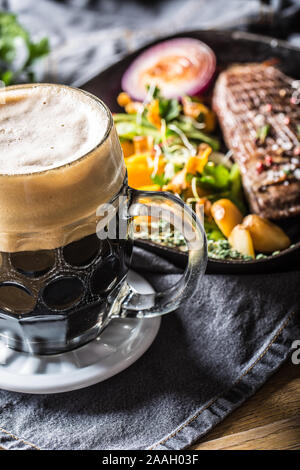 Glas dunkles Bier im Pub oder delicoius restavurant auf Tisch mit Essen. Stockfoto