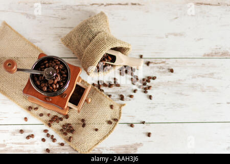 Manuelle vintage Kaffeemühle und Kaffeebohnen in einem sackleinen Tasche auf einem Holztisch. Kopieren Sie Platz. Stockfoto