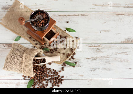 Manuelle vintage Kaffeemühle und Kaffeebohnen in einem sackleinen Tasche auf einem Holztisch. Kopieren Sie Platz. Stockfoto