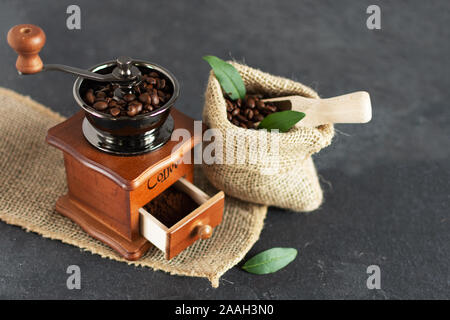 Manuelle vintage Kaffeemühle und Kaffeebohnen in einem sackleinen Tasche auf einem Holztisch. Kopieren Sie Platz. Stockfoto