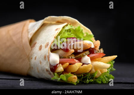 Lecker Döner mit frischem Salat Beilagen und rasiert gebratenes Fleisch, serviert in Tortilla Wraps auf braunem Papier als Snack zum mitnehmen. Stockfoto