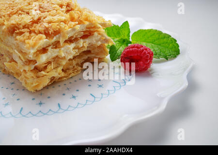 Kuchen Napoleon mit Vanille Milch Sahne auf einem Schild auf weißem Hintergrund Stockfoto