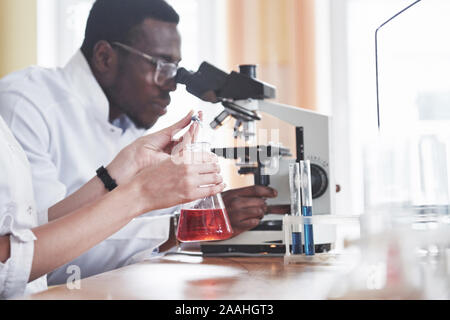 Wissenschaftler arbeiten eng mit dem Mikroskop im Labor durch Experimente und Analysen. Stockfoto