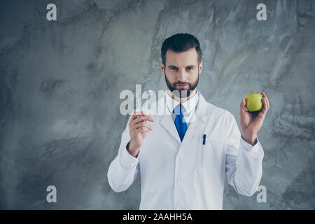 Portrait von qualifizierten erfolgreiche Zahnarzt halten Zahnheilkunde Ausrüstung untersuchen Patienten Zähne Karies cuer halten green apple Zeichen der starken Mundhöhle Verschleiß Stockfoto