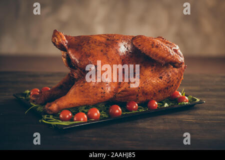 Nahaufnahme Foto von leckeren Hähnchen vom traditionellen Thanksgiving Mahlzeit auf Tray mit grünen Salbei Red Cherry Tomaten auf Holz Tisch serviert über Braun isoliert Stockfoto
