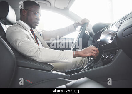 Eleganter schwarzer Geschäftsmann hinter dem Steuer des neuen Luxus Auto sitzen. Reichen afrikanischen amerikanischen Mann Stockfoto