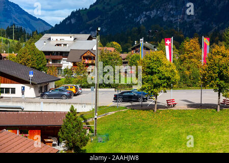 Kandersteg, Schweiz - 17. Oktober 2019: Street View mit bunten Holzhäusern, Schweizer Flagge und Berge Panorama, Kanton Bern, Europa Stockfoto