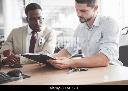 Eine junge attraktive schwarze Unternehmer kauft ein neues Auto, unterzeichnet er einen Vertrag und ist der Schlüssel zu den Manager Stockfoto