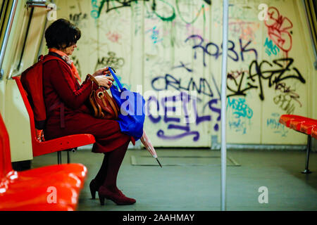 Bukarest, Rumänien - November 19, 2019: eine Frau ist unterwegs in eine schmutzige und alte U-Bahn Waggon voller Graffiti. Stockfoto