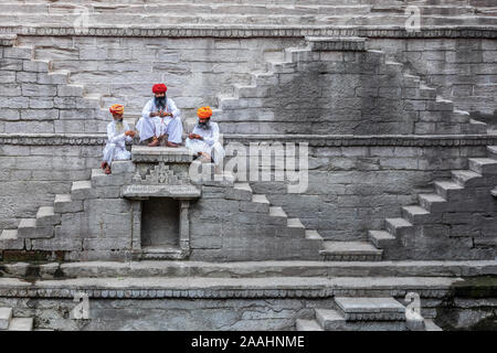 Drei Männer spielen Karten auf den Stufen der stepwell Toorji Ka Jhalra in Jodhpur, Rajasthan, Indien Stockfoto