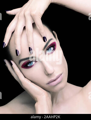 Beautiful young woman touching head and face, black background Stockfoto