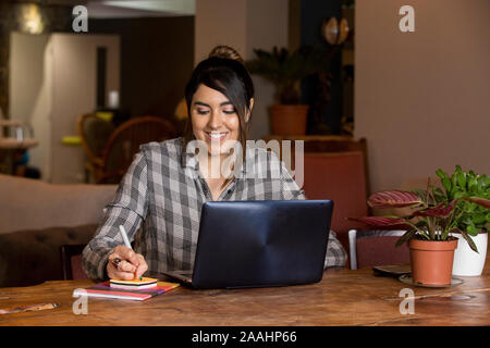 Frau Schreiben und Arbeiten am Laptop im Co-Arbeitsbereich Stockfoto