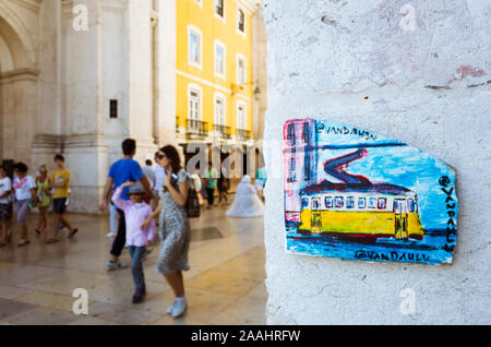 Lissabon, Portugal: Porzellan Plakette entspricht einer alten gelben Straßenbahn an der Rua Augusta Arch. Zufällige Personen im Hintergrund. Stockfoto