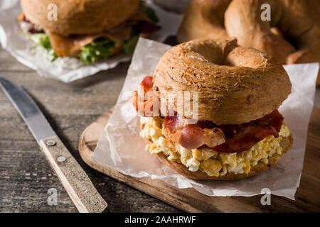 Bagel Sandwich mit Schinken, Ei und Käse auf dem Holztisch. Stockfoto