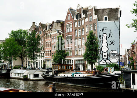 Amsterdam Canal Street Art einschließlich barge, Niederlande, Prinsengracht, Nummer 70, ein wandbild von der Londoner Polizei stilisierter comic Puppen, Pyramide Schuhe Stockfoto