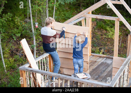 Vater und Sohn bauen Baumhaus im Garten Stockfoto