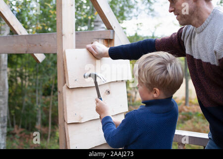 Vater und Sohn bauen Baumhaus im Garten Stockfoto