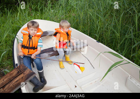 Brüder spielen auf dem Boot im Gras Feld günstig Stockfoto