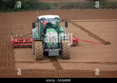 Bauer bei der Arbeit der Aussaat Grassamen für die neue Saison mit einer drillmaschine oder Pflanzmaschine in Cornwall, England. Stockfoto