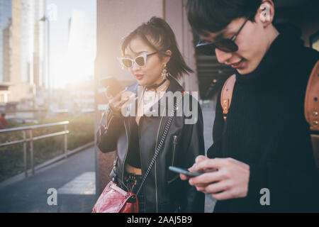 Junges Paar mit Handy beim Gehen auf die Straße, Mailand, Italien Stockfoto